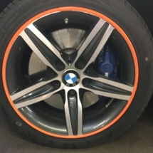 Close Up View Of A Single Silver BWM Alloy Wheel With A Orange AlloyGator Wheel Protector