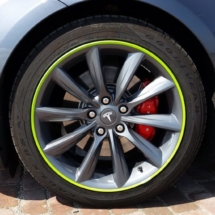 Close Up View Of Grey Tesla Model S Silver Alloy Wheel With Green AlloyGator Wheel Protector & Red Callipers
