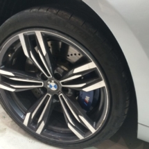 Close Up Of A BMW Dimond Cut Black And Silver Alloy Wheels, Black AlloyGator Wheel Protector And Blue Break Callipers