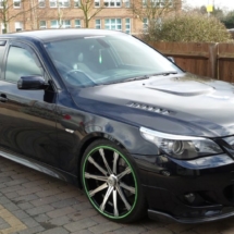 Side View Of Modified Black BMW With Custom Silver Alloy Wheels And Green AlloyGator Wheel Rim Protectors