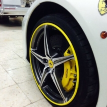Side View Of A White Ferrari Front Alloy Wheel With Yellow AlloyGator Alloy Wheel Protector And Yellow Brake Callipers