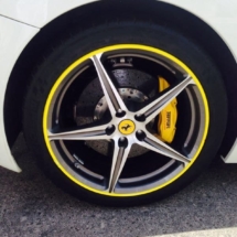 Side View Of A White Ferrari Front Alloy Wheel With Yellow AlloyGator Wheel Rim Protector And Yellow Brake Callipers